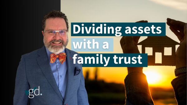 Bearded man with glasses in a suit with a bow tie next to a family at sunset.