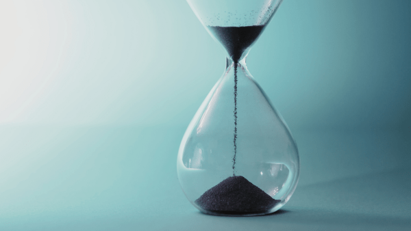 Hourglass with sand flowing to bottom on a bluish background