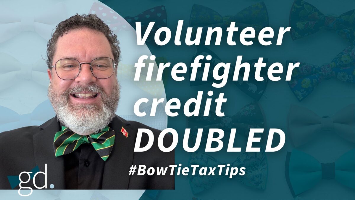 White man with short dark curly hair, whitish beard and glasses wearing a blue and green bow tie with dark suit jacket and dark shirt talking about volunteer firefighter tax credit
