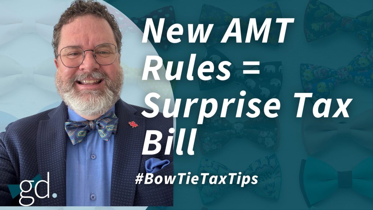 White male with dark curly hair, a whitish beard, glasses, and a blue patterned bow tie with blue shirt and blue suit jacket talking about Alternative minimum tax Canada.