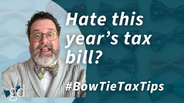 White male in glasses and short dark hair with surprised look, wearing a bow tie and gray sweater with white shirt talking about being happy with your tax bill