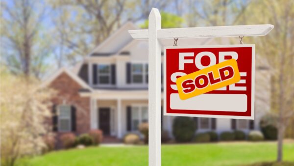 Sold sign in front of a two story brick and white siding house surrounded by trees and grass to represent PREC benefits for realtors in Canada